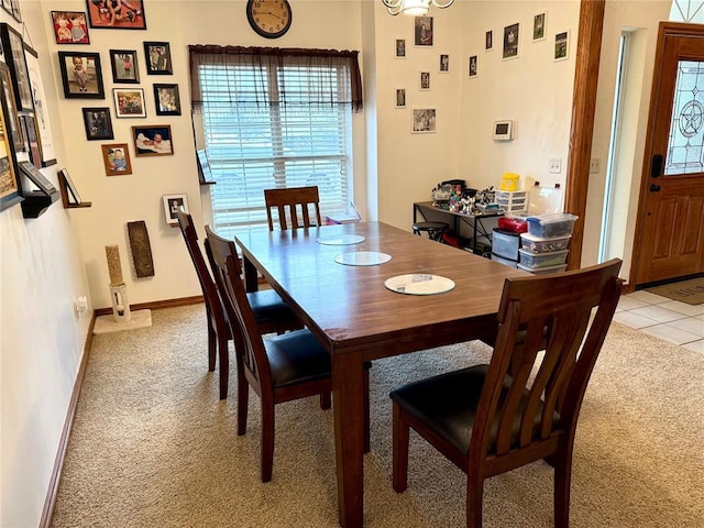 dining space featuring baseboards, light tile patterned floors, and light carpet