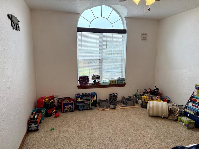 game room with a textured wall, carpet, a textured ceiling, and ceiling fan