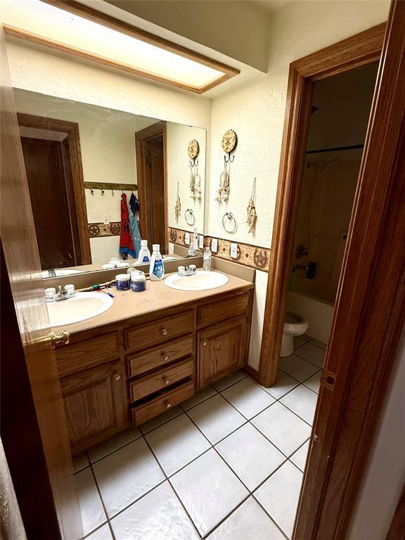 bathroom featuring toilet, tile patterned flooring, a sink, and double vanity