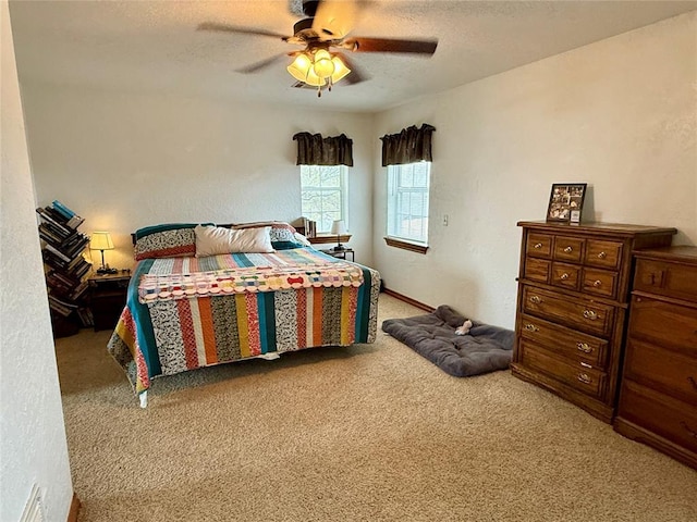 carpeted bedroom featuring a ceiling fan, a textured wall, and a textured ceiling