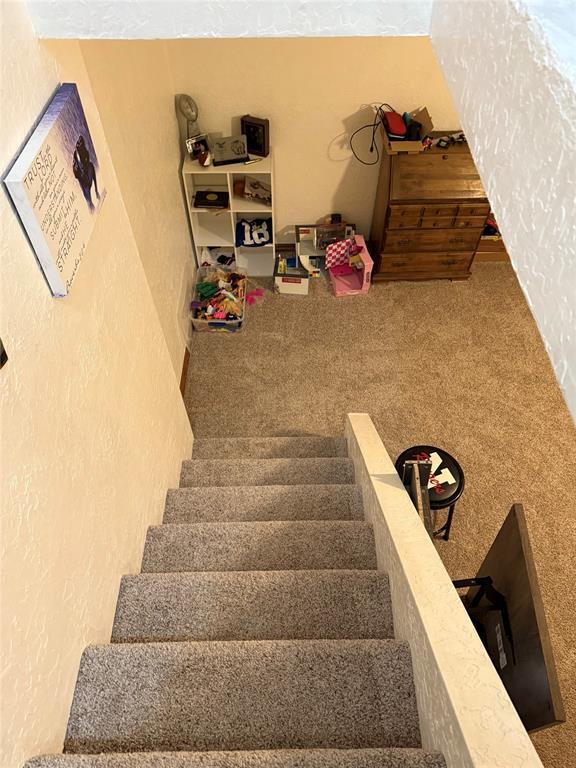 staircase featuring carpet flooring and a textured wall