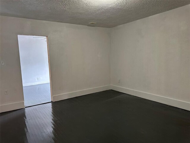 314 N Maryland Ave, Mangum, OK 73554 - unfurnished room featuring dark wood-style floors, baseboards, and a textured ceiling