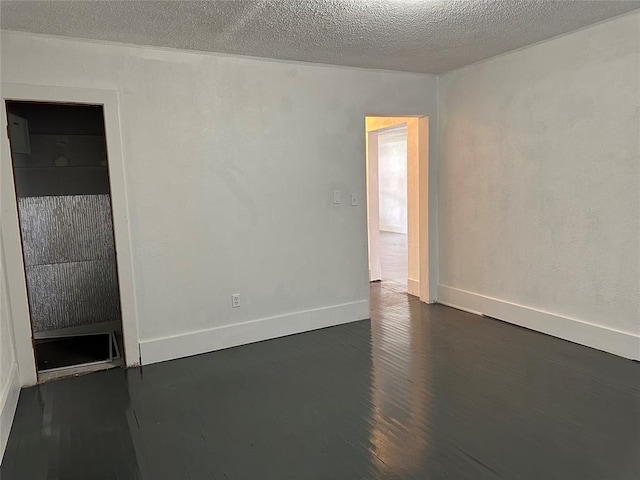 314 N Maryland Ave, Mangum, OK 73554 - spare room with baseboards, dark wood-style flooring, and a textured ceiling