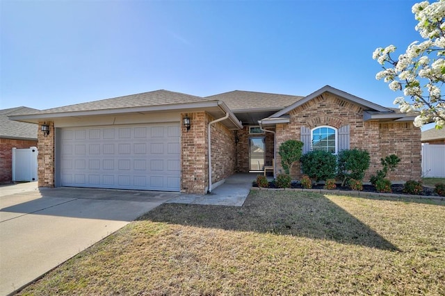 ranch-style home featuring a garage, a front yard, brick siding, a shingled roof, and concrete driveway