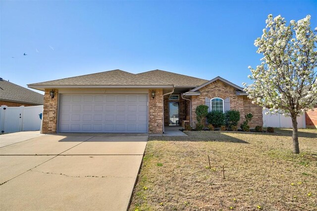 ranch-style home with concrete driveway, a front lawn, an attached garage, brick siding, and fence