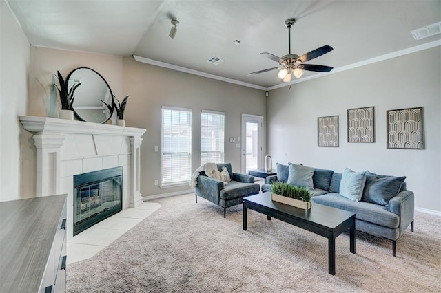 living room featuring ornamental molding, visible vents, a ceiling fan, and light colored carpet