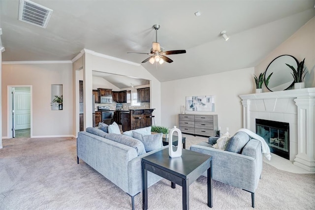 living room with vaulted ceiling, a tiled fireplace, visible vents, ceiling fan, and light colored carpet