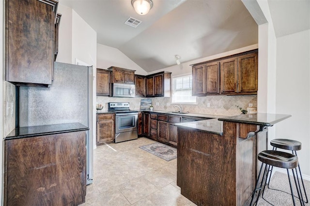 kitchen with a peninsula, dark brown cabinets, visible vents, lofted ceiling, and stainless steel appliances
