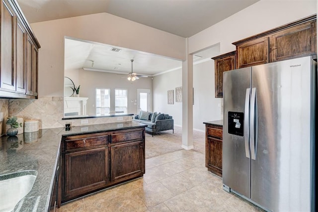 kitchen with dark brown cabinetry, stainless steel fridge, a peninsula, a ceiling fan, and decorative backsplash