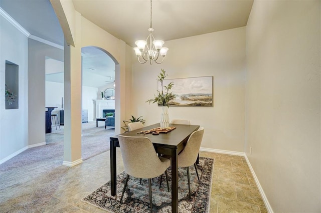 dining room featuring baseboards, arched walkways, a fireplace, and ceiling fan with notable chandelier
