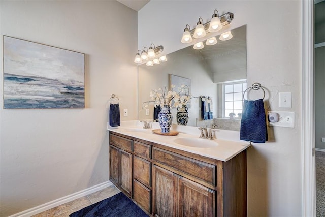 bathroom with a sink, tile patterned floors, baseboards, and double vanity