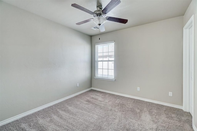 carpeted spare room with visible vents, ceiling fan, and baseboards