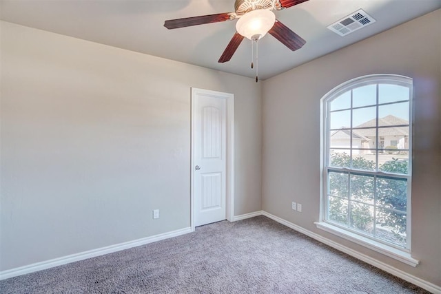 carpeted empty room with visible vents, baseboards, and ceiling fan