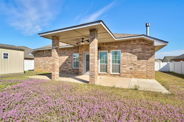 rear view of house with ceiling fan, a lawn, a patio area, fence, and brick siding