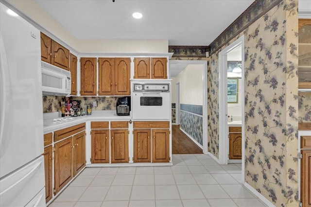 6706 N Woodward Dr, Oklahoma City, OK 73116 - kitchen with white appliances, wallpapered walls, light countertops, brown cabinetry, and baseboards