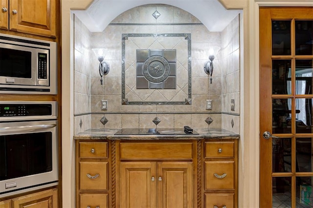 815 River View Dr, Norman, OK 73071 - kitchen with dark stone counters, brown cabinets, stainless steel appliances, and tasteful backsplash