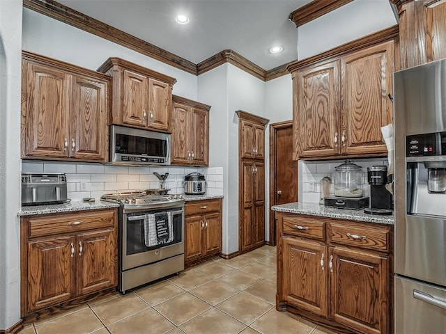 kitchen featuring light stone countertops, crown molding, backsplash, and appliances with stainless steel finishes