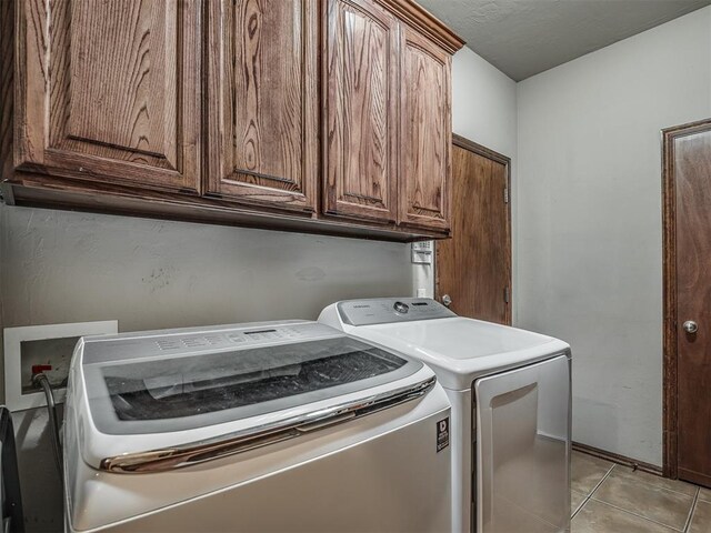 washroom featuring light tile patterned flooring, washing machine and dryer, and cabinet space