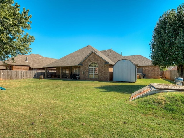 back of house with a fenced backyard, an outdoor structure, a lawn, and a shed