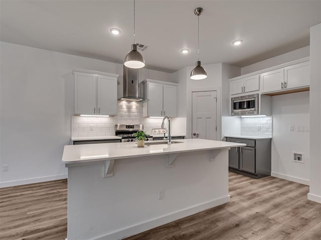 kitchen with tasteful backsplash, visible vents, wall chimney exhaust hood, a sink, and appliances with stainless steel finishes