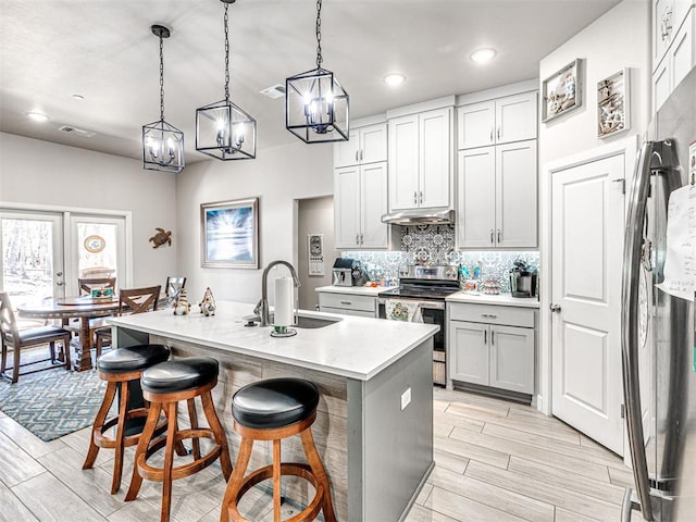 21608 SE 95th St, Mcloud, OK 74851 - kitchen with appliances with stainless steel finishes, under cabinet range hood, a sink, a breakfast bar area, and wood finish floors