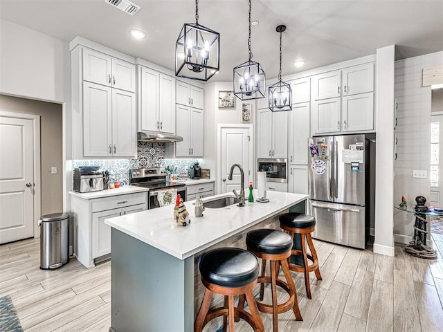 21608 SE 95th St, Mcloud, OK 74851 - kitchen with appliances with stainless steel finishes, a sink, under cabinet range hood, a chandelier, and light wood-style flooring