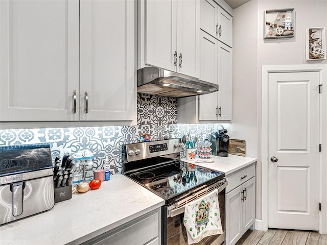 21608 SE 95th St, Mcloud, OK 74851 - kitchen featuring stainless steel electric range oven, under cabinet range hood, tasteful backsplash, light wood finished floors, and light stone countertops