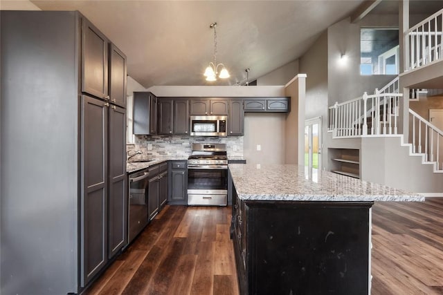 kitchen featuring stainless steel appliances, an inviting chandelier, backsplash, a kitchen island, and dark wood-style flooring