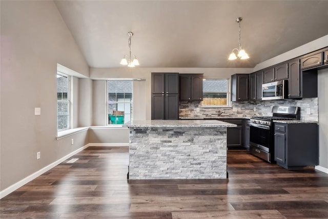 kitchen with decorative backsplash, an inviting chandelier, appliances with stainless steel finishes, and lofted ceiling