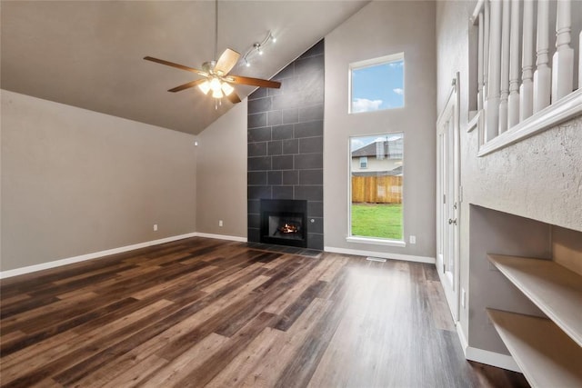 unfurnished living room featuring wood finished floors, baseboards, a fireplace, high vaulted ceiling, and ceiling fan