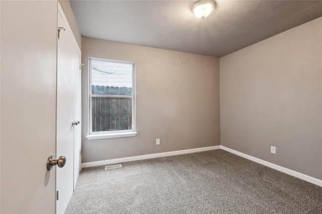 spare room with carpet floors, visible vents, and baseboards