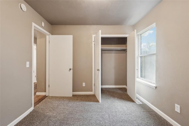 unfurnished bedroom featuring baseboards, carpet floors, and a closet