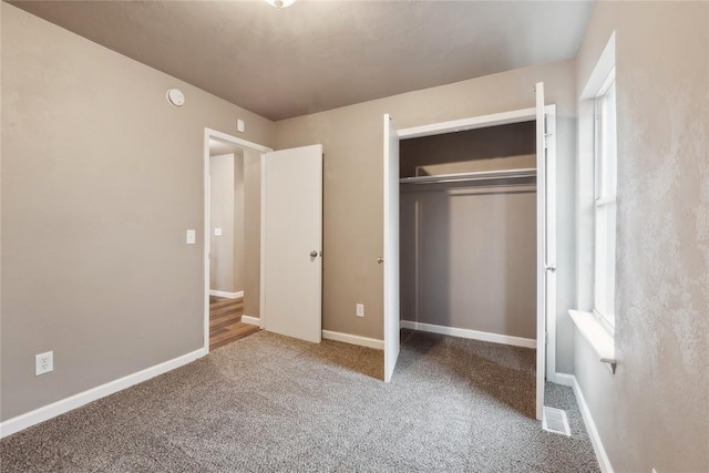 unfurnished bedroom featuring baseboards, carpet floors, and a closet