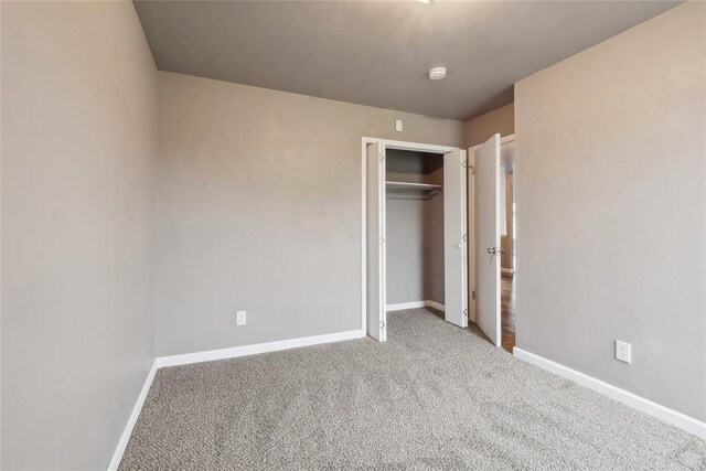 unfurnished bedroom with baseboards, carpet floors, and a closet