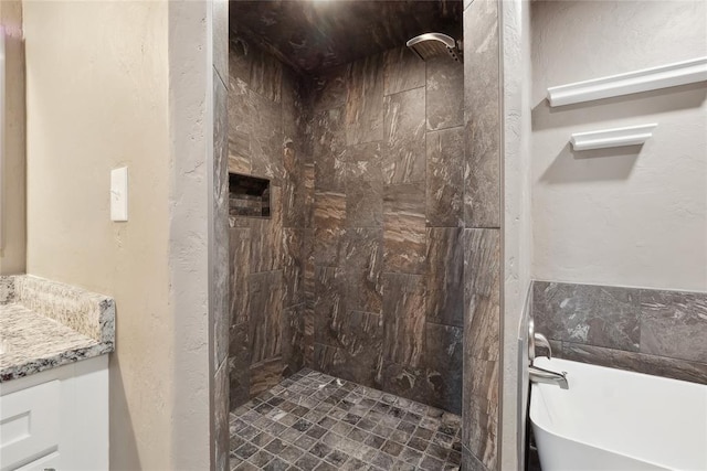 bathroom featuring a freestanding bath, vanity, and tiled shower