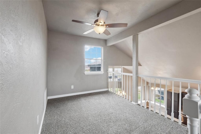unfurnished room with a textured wall, vaulted ceiling with beams, baseboards, carpet flooring, and ceiling fan