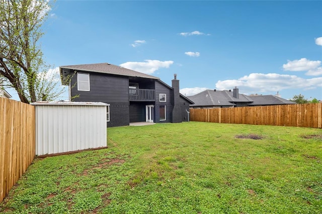 back of property featuring a fenced backyard, a yard, and a storage unit