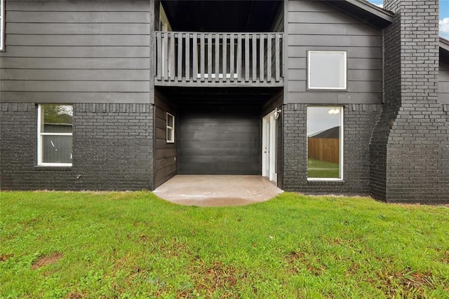 rear view of property with a balcony, a yard, and brick siding