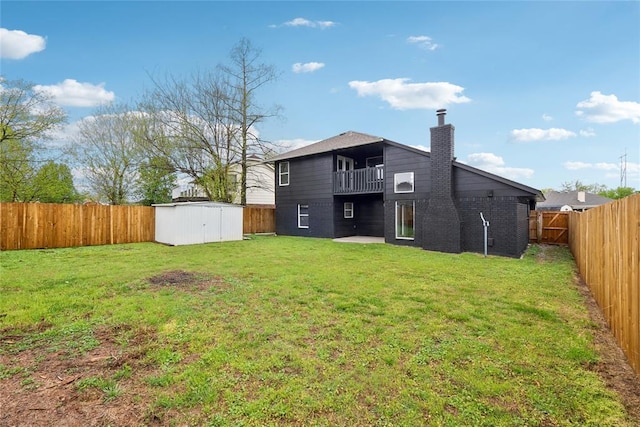 back of house featuring a balcony, a storage shed, a chimney, a fenced backyard, and an outdoor structure