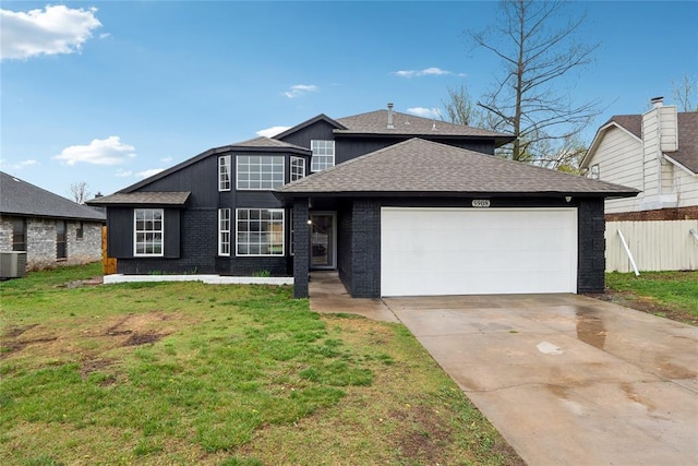 traditional-style home featuring concrete driveway, fence, a garage, a shingled roof, and a front yard
