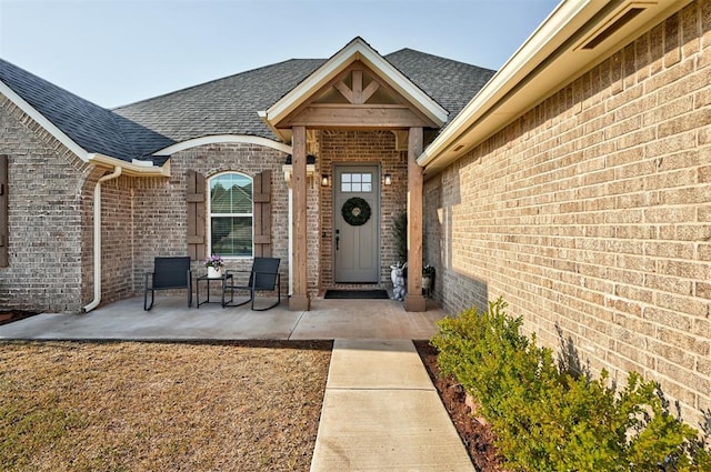 property entrance with brick siding and a shingled roof
