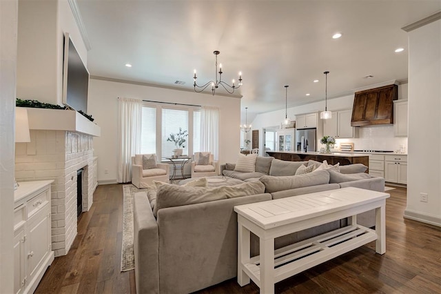 living area featuring crown molding, an inviting chandelier, a fireplace, dark wood finished floors, and recessed lighting
