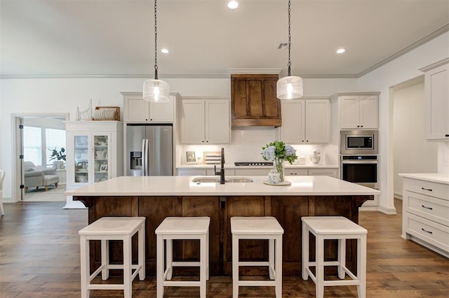 kitchen featuring a sink, ornamental molding, a kitchen island with sink, a kitchen bar, and stainless steel appliances
