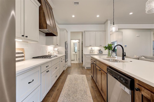 kitchen featuring custom range hood, dark wood-type flooring, visible vents, appliances with stainless steel finishes, and a sink