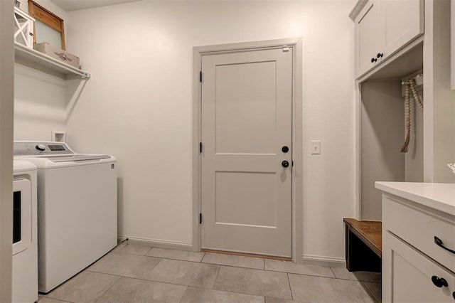 clothes washing area with independent washer and dryer, light tile patterned floors, baseboards, and cabinet space