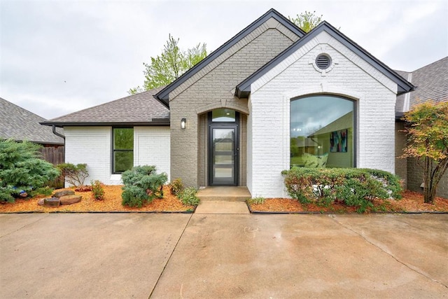 view of front of property with brick siding and a shingled roof