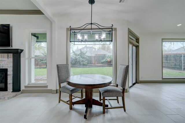 dining area with a healthy amount of sunlight, a fireplace, visible vents, and an inviting chandelier