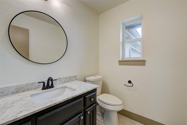 bathroom with baseboards, toilet, and vanity