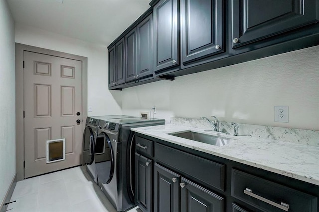 clothes washing area with a sink, cabinet space, and separate washer and dryer