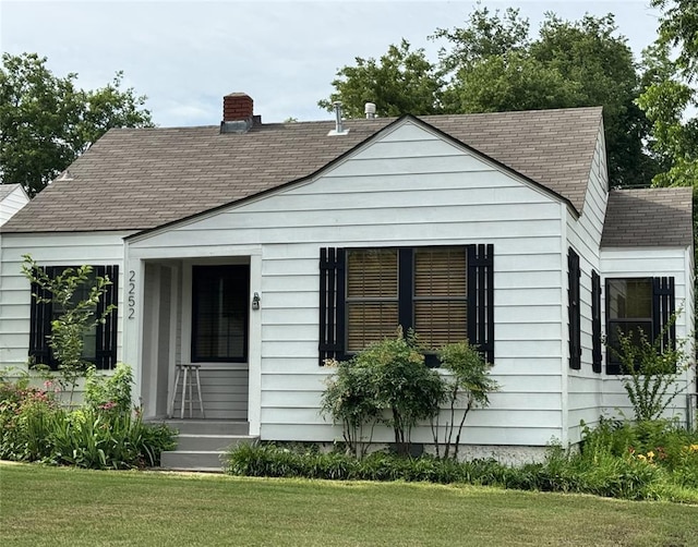 2252 NW 37th St, Oklahoma City, OK 73112 - view of side of property with a shingled roof, a lawn, and a chimney